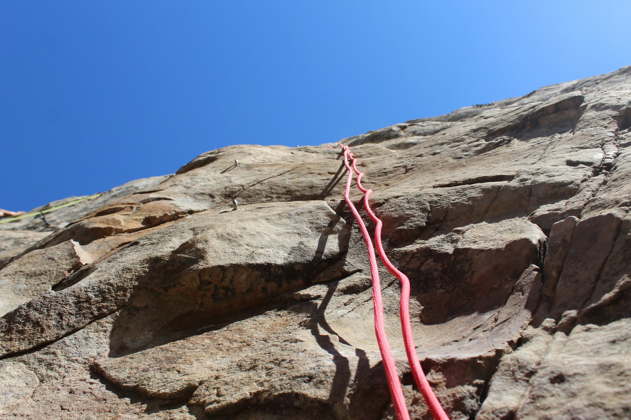 A climber celebrating reaching the summit with raised arms against a mountain backdrop