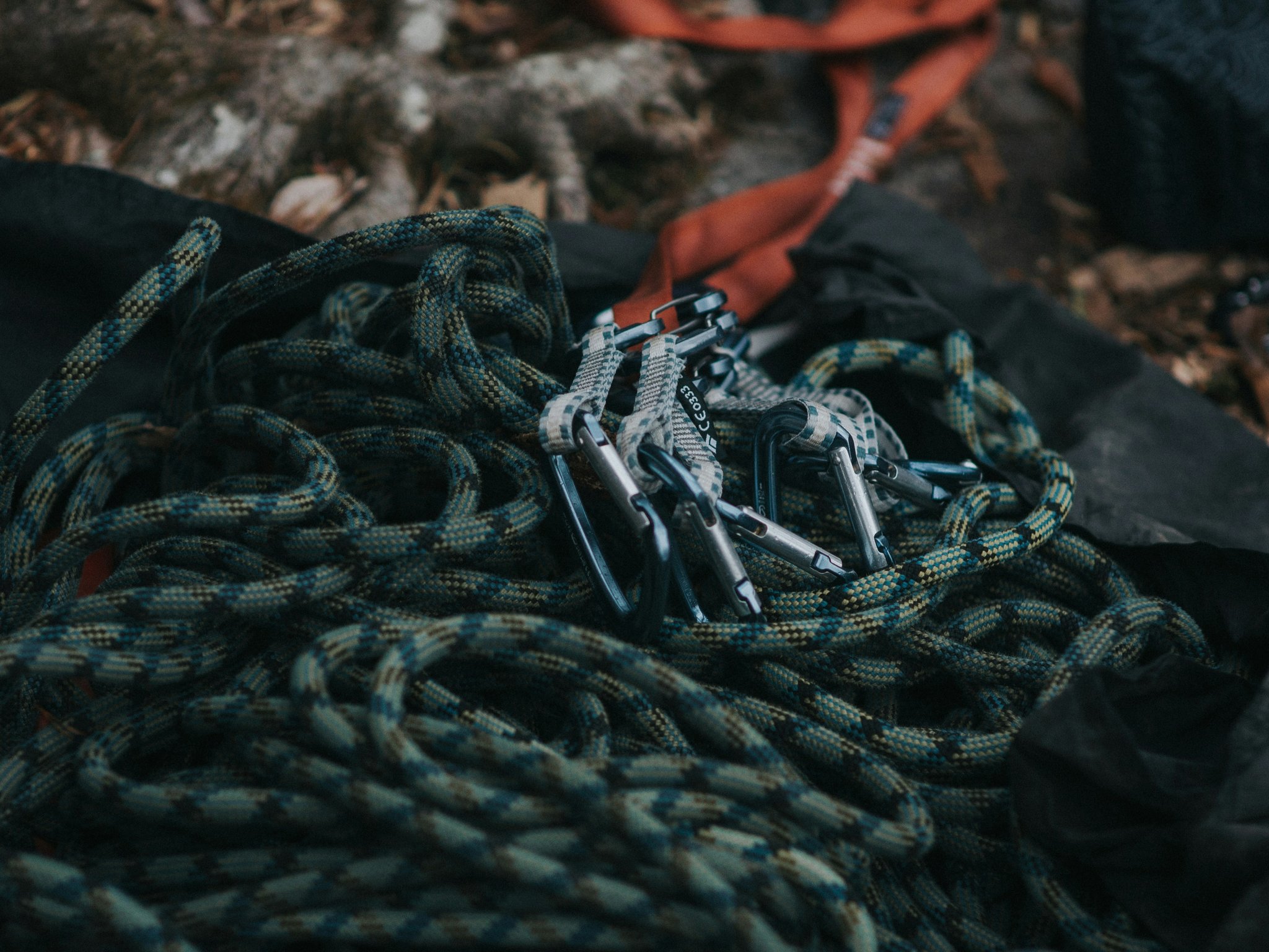 Climbing protection gear including cams, nuts, and slings on a rock wall